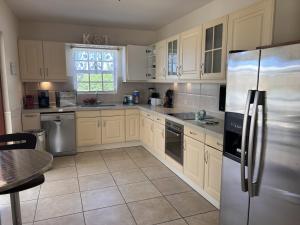 una cocina con armarios blancos y electrodomésticos de acero inoxidable en Villa Jolie, en Noord