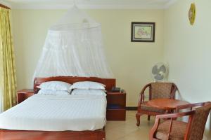 a bedroom with a bed and a desk and a chair at JEVINE HOTEL in Kampala