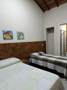 a bedroom with two beds and two paintings on the wall at Pousada Alto da Marina in Búzios