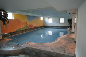 a swimming pool with a painting on the wall at Hotel Sonnenhof in Castelrotto