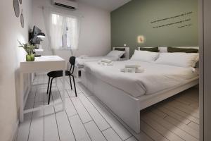 een witte slaapkamer met een groot bed en een bureau bij Gioiello Fiorentino - Duomo 2 minuti a piedi in Florence