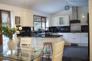 cocina con armarios blancos y mesa de cristal en Home in Rugby Warwickshire, 
