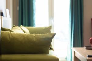- un canapé vert avec des oreillers en face d'une fenêtre dans l'établissement GPX-CLR TheGreenFamilySuite, à Larissa