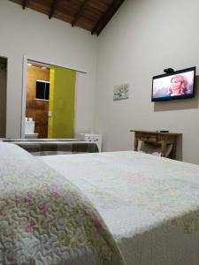 a bedroom with a bed and a tv on the wall at Pousada Alto da Marina in Búzios