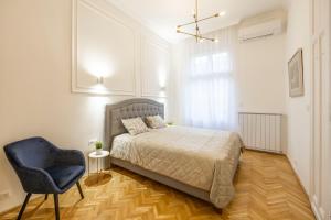 a bedroom with a bed and a blue chair at Luxurious Central 4BEDRM 3BATHRM Residence w/ Balcony in Budapest