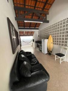 un sofá de cuero negro en una sala de estar con tabla de surf en Big House, 30 metros do mar, en Bombinhas