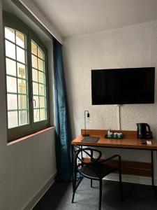 a desk with a television and a chair in a room at Hôtel De La Loge in Perpignan