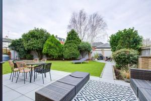 un patio con mesa y sillas y un jardín en Chic 4-BR Home w/ Hot Tub & BBQ in Hornbeam Lane, en Chingford