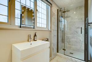 y baño con lavabo blanco y ducha. en Chic 4-BR Home w/ Hot Tub & BBQ in Hornbeam Lane, en Chingford