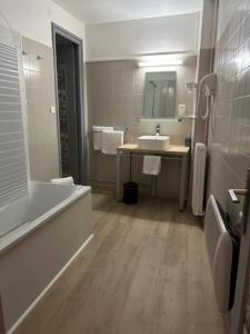 a bathroom with a tub and a sink and a bath tub at Hôtel De La Loge in Perpignan