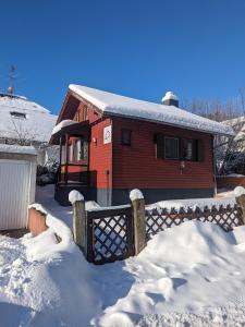 ein rotes Haus mit einem Zaun im Schnee in der Unterkunft Ferienhaus Tinyhouse21 Wasserkuppe in Gersfeld