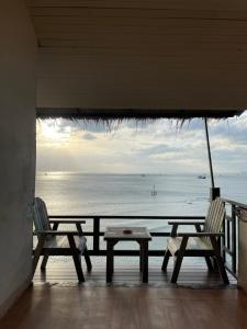 Duas cadeiras e uma mesa numa varanda com vista para o oceano em Suncliff Resort em Haad Rin