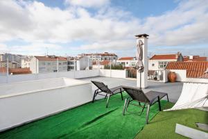 patio z 2 krzesłami i parasolem na dachu w obiekcie Apartamento da Alegria w mieście Caldas da Rainha