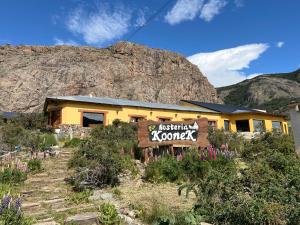 a yellow building with a sign in front of a mountain at Hosteria Koonek in El Chalten