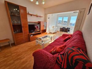 een woonkamer met een rode bank en een televisie bij Apartamento Edificio Florida in Benidorm
