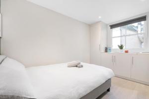 a white bedroom with a bed and a window at Quaint Mews Home in Chelsea in London