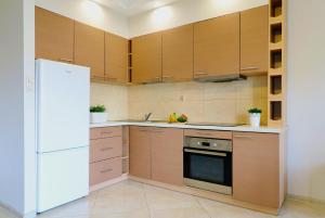 a kitchen with wooden cabinets and a white refrigerator at Apartament z dziedzińcem koło rzeki in Ełk