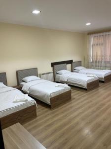 three beds in a room with wooden floors at Kvartira in Quba