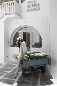 une femme est assise sur une charrette remplie de pastèques dans l'établissement Terra Maria Hotel, à Mykonos