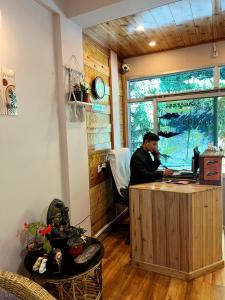 un hombre sentado en un escritorio con un portátil en Darjeeling Heights - A Boutique Mountain View Homestay, en Darjeeling