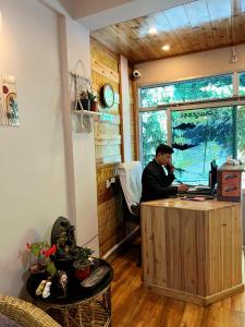 a man sitting at a desk with a laptop at Darjeeling Heights - A Boutique Mountain View Homestay in Darjeeling