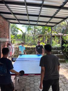 a group of men standing around a ping pong table at JOGLO Greenhouse in Ngemplak
