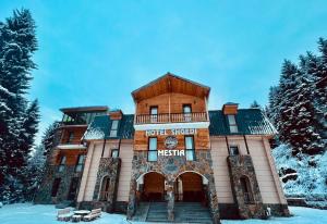 a building with a clock on it in the snow at Hotel Shgedi Mestia in Mestia