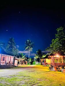a group of buildings and palm trees at night at JOGLO Greenhouse in Ngemplak