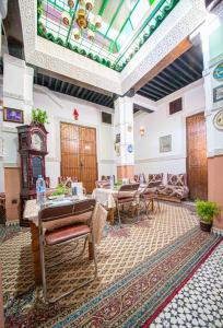 una grande stanza con orologio e tavoli e sedie di Riad Fes Basma a Fes