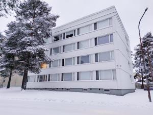 un edificio bianco con neve di fronte ad un albero di Arctic Foxy Studio a Rovaniemi