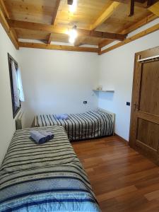 two beds in a room with wooden ceilings at NEW ENTRY - Nuova villa nel verde in Mezzana