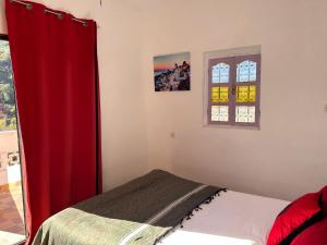 - une chambre avec un lit et un rideau rouge dans l'établissement Chez Yahia, Au coeur de L'Ourika, à Ourika