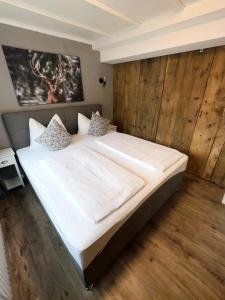 a bedroom with a large white bed with wooden walls at Casa Enrico in Oberjoch