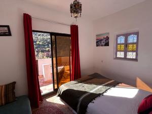 a bedroom with a bed with red curtains and a window at Chez Yahia, Au coeur de L'Ourika in Ourika