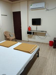 a room with two beds and a tv on a wall at Samraj Lodge in Akalkot