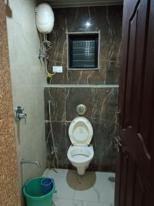 a small bathroom with a toilet and a bucket at Samraj Lodge in Akalkot