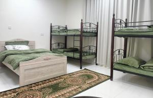 alshahad chalet في Bārsit: غرفة نوم مع ثلاثة أسرة بطابقين وسجادة