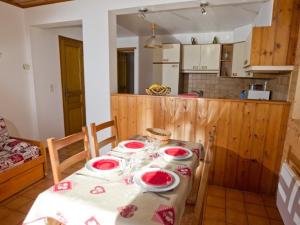 una cocina con una mesa con platos rojos. en Appartement Saint-Chaffrey , 2 pièces, 4 personnes - FR-1-762-19, en Saint-Chaffrey