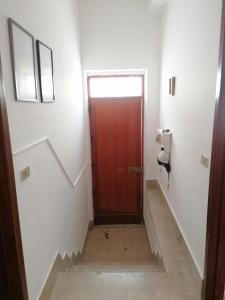 escalera con puerta marrón en una habitación blanca en Stanza con terrazza, en Calamonaci