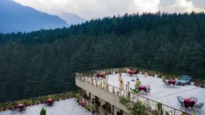 un balcón de un edificio con mesas y sillas en Snow Valley Resorts & Spa Manali, en Manali