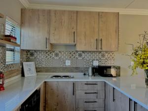 una cocina con encimeras blancas y armarios de madera en The Acorn @ Skyfall Country Estate, en Polokwane