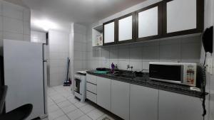 Il comprend une cuisine blanche équipée d'un four micro-ondes et d'une cuisinière. dans l'établissement Apartamento sossegado no Universitário 704, à Caruaru