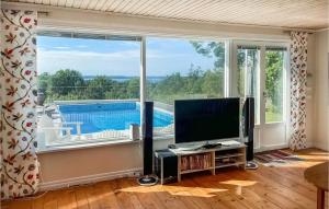 a living room with a tv and a large window at Nice Home In Frjestaden With House Sea View in Färjestaden