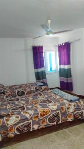 a bed in a bedroom with purple curtains at Alexandria BLUE Wave in Alexandria