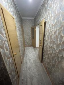 einen leeren Flur mit zwei Türen und einer Wand mit Tapeten in der Unterkunft Квартира в центре города,в ЖК Куралай in Qysylorda