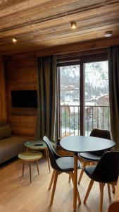 a living room with tables and chairs and a large window at RESIDENCE GRAND COCOR -Studio 25 m2- in Val-d'Isère