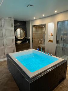 un bagno con doccia e ampia vasca blu. di Nid d’Angers - Spa, Sauna privatifs & Écran cinéma ad Angers