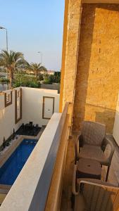 a balcony with a bench and a chair next to a pool at Royal Elegance Room in Sheikh Zayed