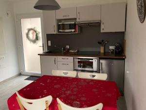 une cuisine avec une table rouge et des chaises blanches dans l'établissement Gites au jardin, à Morsbronn-les-Bains