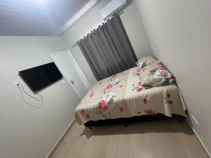 a small bedroom with a bed and a flat screen tv at Boicy Residence in Foz do Iguaçu